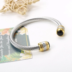 Detail of twisted cable steel bangle featuring black agate ends and gold accents
