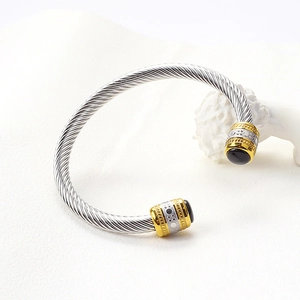 Macro detail of silver cable cuff bracelet with gold rings and black onyx stone ends