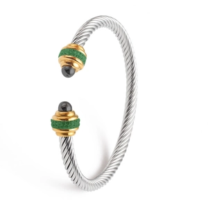 Two-tone twisted cable bangle with green accents and gold tips on a white background