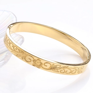 Détail d'un jonc en acier inoxydable doré 8mm avec motifs floraux sur plateau