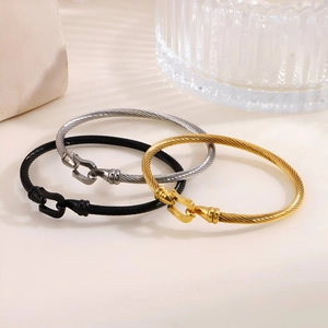 Detailed set of cable wire bracelets in gold, silver and black with horseshoe clasps