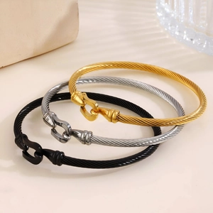 Three twisted cable steel bracelets with horseshoe shackle clasps in gold, silver, and black
