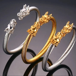 Dettaglio di tre bracciali a fune con teste di drago in argento, oro e finitura bicolore