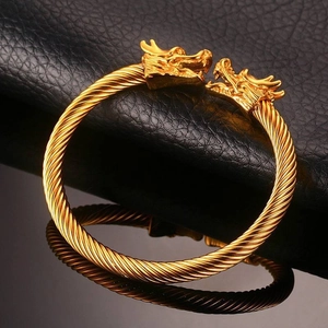 Dettaglio del bracciale a doppia testa di drago dorata con trama in acciaio intrecciato