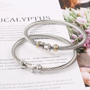 Classic stainless steel cable twist bangles in silver and gold tones on a magazine