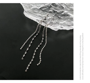 Detail of silver long tassel earrings with sparkling crystals on minimalist ice-like background