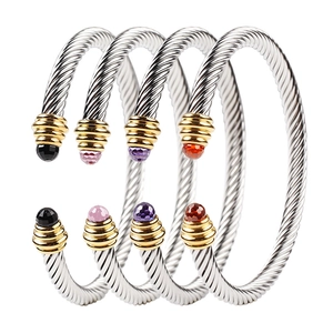 Macro detail of twisted cable bracelets with assorted gemstones and golden end caps
