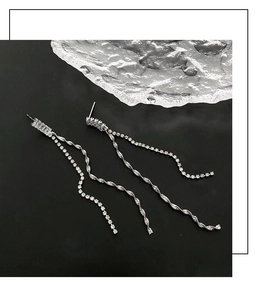 Close-up of silver tassel earrings with rectangular zircon and twisted metal chains
