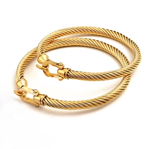 Close-up of golden horseshoe buckle bracelets with detailed braided rope texture design