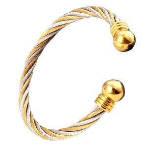Macro view of two-tone braided stainless steel cable bracelet with gold sphere ends