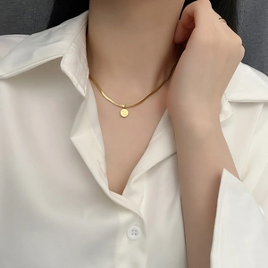 Collier maille serpent dorée avec pendentif rond Good Luck porté par un mannequin