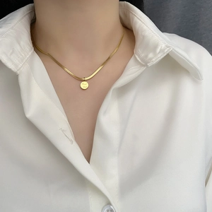 Collier élégant en chaîne serpent dorée avec pendentif rond gravé Good luck porté