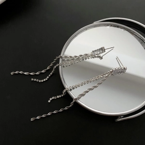 Elegant silver tassel earrings with zircon stones on mirror background