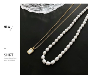Close-up of titanium steel necklace with white shell pendant and freshwater pearl strand