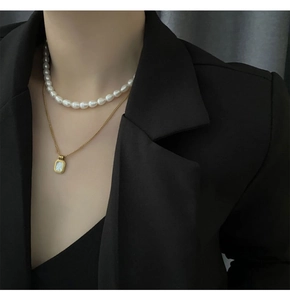 Detail of layered gold necklace with white freshwater pearls and shell pendant on model