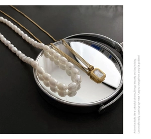 Detail view of layered freshwater pearl necklace and gold titanium steel shell pendant set