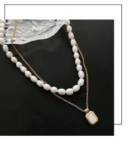 Close-up of double layered necklace with freshwater pearls and a gold geometric pendant