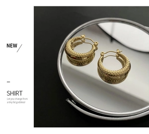 Detailed view of gold hoop earrings with intricate snake scale texture on mirror surface