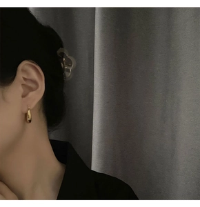 Close-up of elegant gold teardrop earrings with mirror finish on model's ear