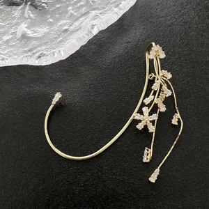 Nahaufnahme der goldenen Blumen-Ohrklemme mit funkelnden Zirkonen und langen Fransen