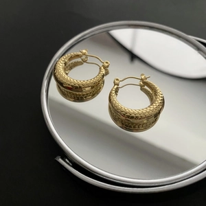 Minimalist gold hoop earrings with delicate snake scale texture on black background