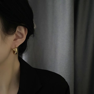 Minimalist gold hoop earrings in polished titanium steel worn on model for daily style