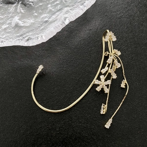Eleganter goldener Blumen-Ohrring mit funkelnden Zirkonia-Kristallen auf schwarzem Grund