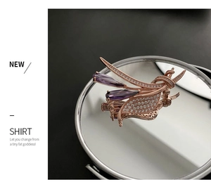 Vue détaillée d'une broche en or rose avec pierres violettes sur surface miroir