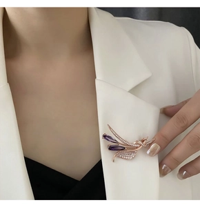 Gros plan d'une broche en zircon violet doré rose sur un revers de veste blanc