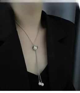 Vue détaillée d'un collier de perles en Y argenté sur un mannequin en blazer noir