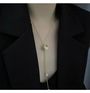 Collier doré ajustable avec perles sur blazer noir, montrant le détail coulissant