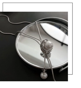 Détail d'un collier chaîne serpent argenté avec perles artistiquement enveloppées sur miroir