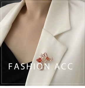 Macro detail of red zircon heart brooch on white blazer lapel with rose gold finish