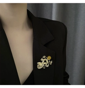 Detalle de un broche de dragón dorado con cristales blancos en solapa negra