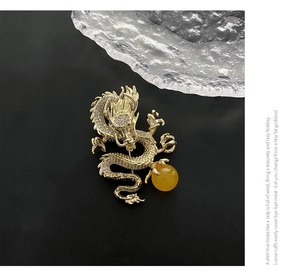 Detalle macro de un lujoso broche de dragón dorado con cristales y una cuenta amarilla