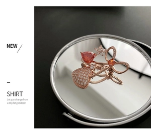 Macro detail of red heart zircon brooch on a mirror with rose gold metal finish