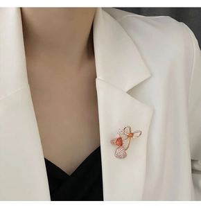 Close-up of rose gold bow brooch with red zircon heart and sparkling rhinestones