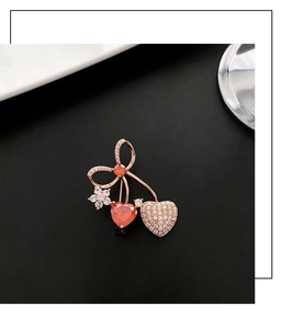 Close-up of cherry brooch with red heart stone and micro-pave crystals on rose gold plating
