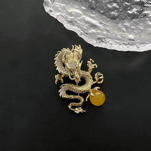 Elegante broche de dragón dorado con circonitas blancas y perla de ámbar sobre fondo negro