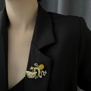 Lujoso broche de dragón dorado con cuenta amarilla y cristales sobre blazer negro
