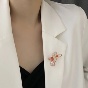 Elegant rose gold heart and bow brooch with red zircon stones on white blazer suit