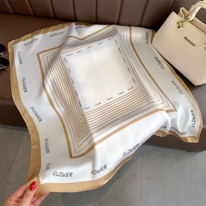 Detail of silk satin scarf with golden geometric borders and Flower print on leather