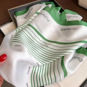 Close-up of soft satin square scarf with green geometric stripes and flower text print