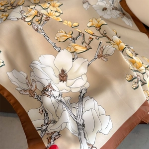 Close-up of silky magnolia floral scarf showing elegant fabric texture and print details