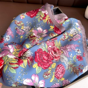 Detailed view of floral silk scarf with vibrant flower prints and purple silk edges