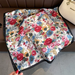 Detail of floral print silk scarf with black satin border on a leather display