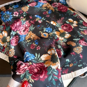 Detail of silk scarf with floral rose print on black satin fabric with smooth texture