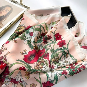 Detail of floral silk scarf with red poppy print and soft pink satin texture