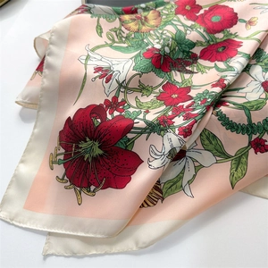 Close-up of floral print satin scarf with red poppy and lily patterns in elegant folds