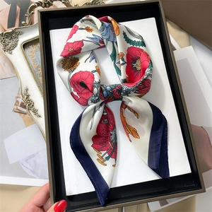 Close-up of floral pattern silk scarf with red poppies and yellow daisies in a gift box
